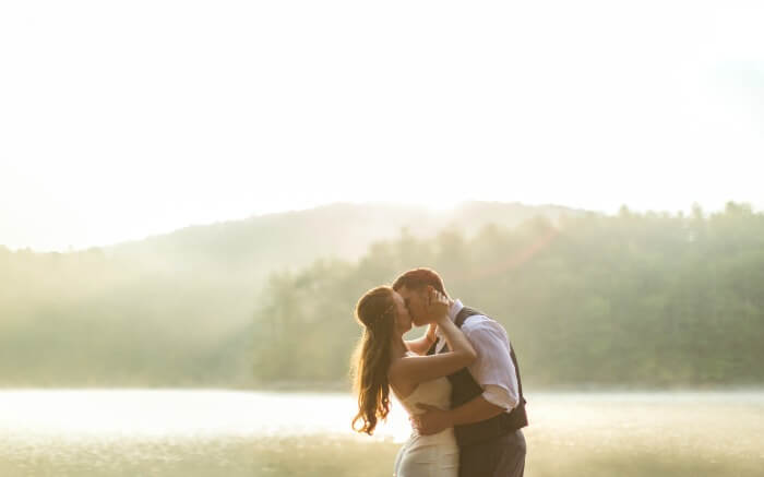 a couple kissing each other as the sun shines in the background