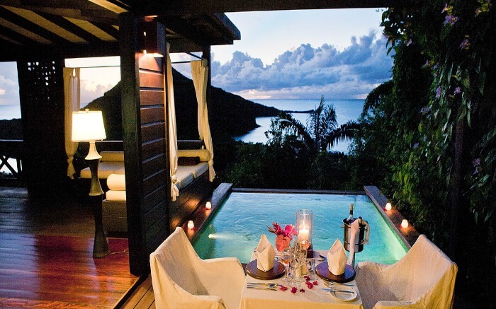 a romantic dining setting beside a pool overlooking the sea