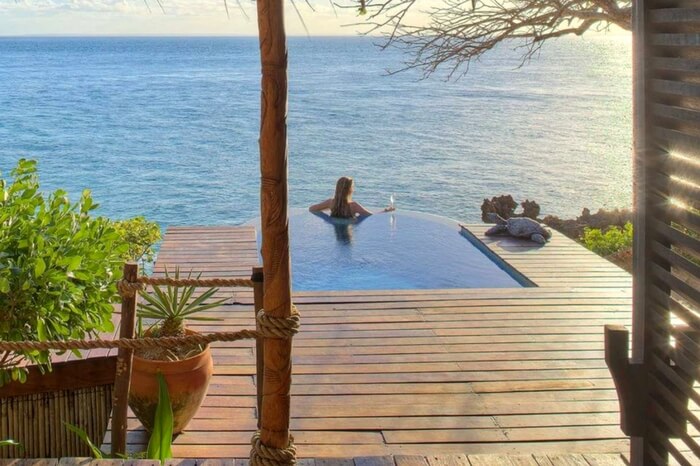 A woman looking at the ocean while relaxing in an infinity pool in a lodge in Mozambique