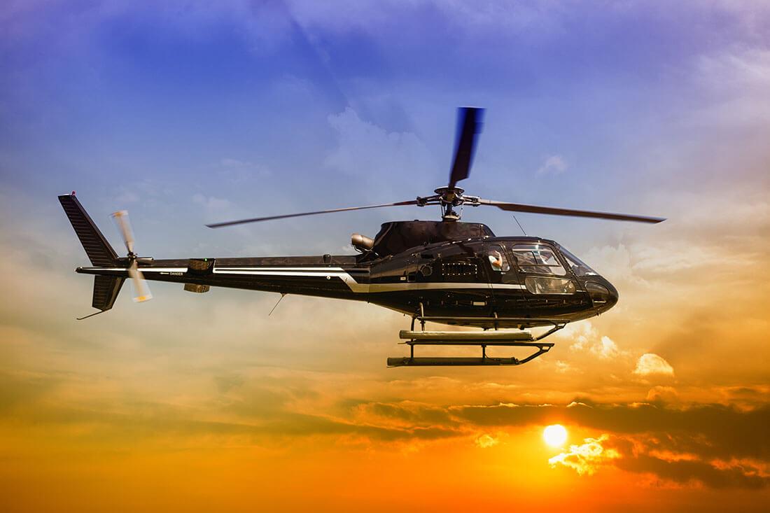 a helicopter flying in a blue and orange sky