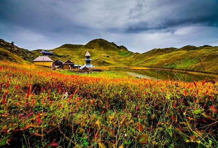 A shot of the Prashar Lake and temple taken by a traveler trekking a hill overlooking the valley