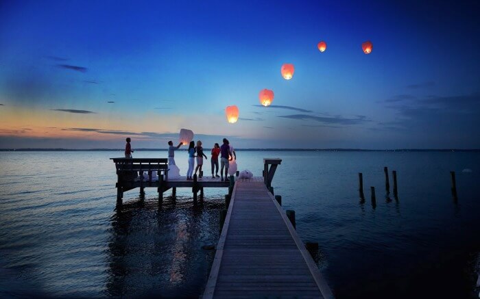 people releasing floating lanterns from a pier