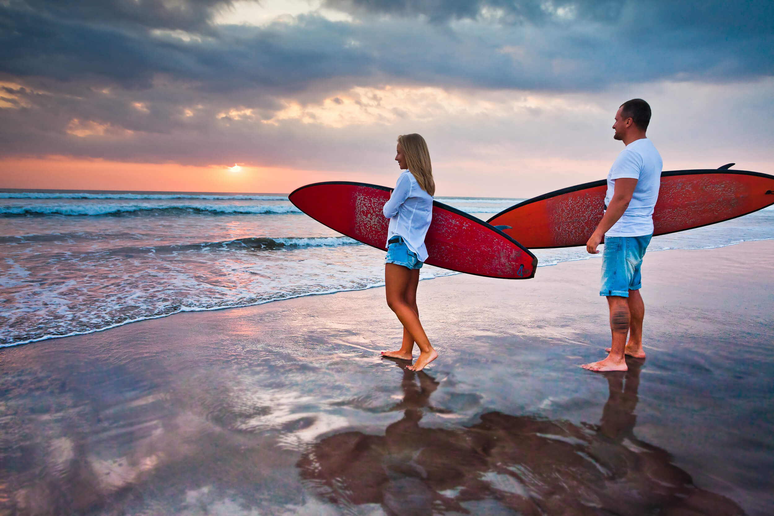 a couple holding surfing board on a beach