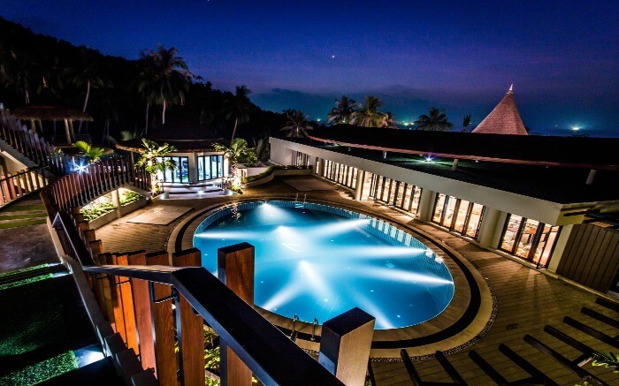 An outdoor pool in a hotel glowing at night