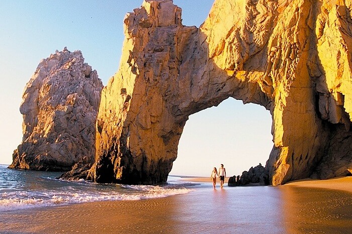A couple on their honeymoon in Mexico takes a walk at the Sunny Lovers Beach in Los Cabos