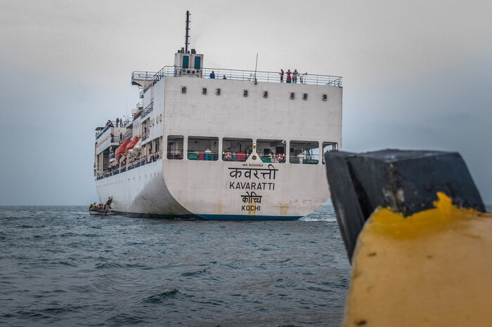 Wooden fishing boat heading towards cruise ship Kavaratti