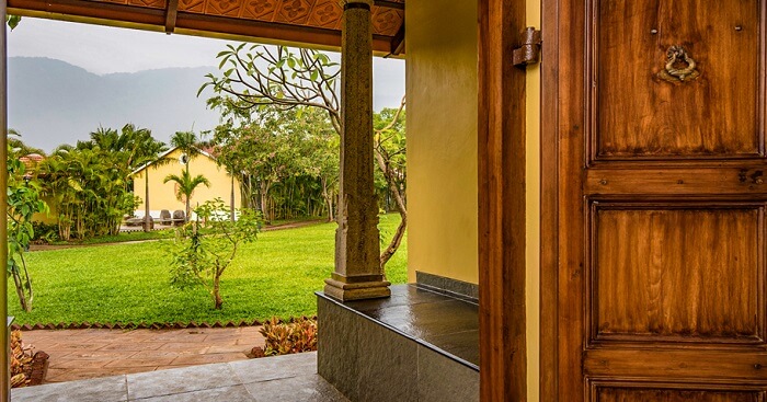 A shot of the lawn and cottages from inside another cottage at Dvara Siruvani Resort in Coimbatore