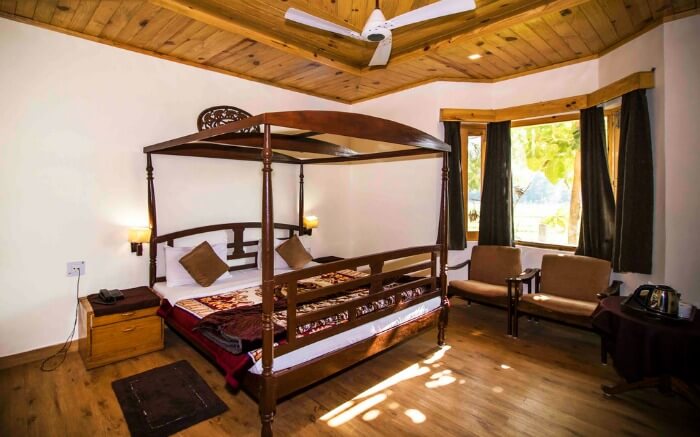 hotel room with wooden bed, sofas, and a glass window