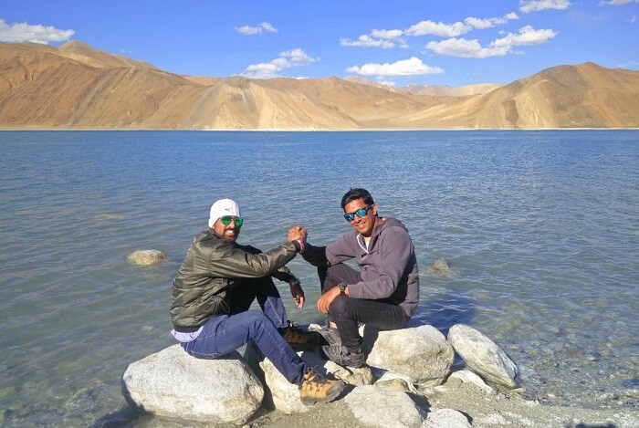 ninad and friend sitting near pangong lake