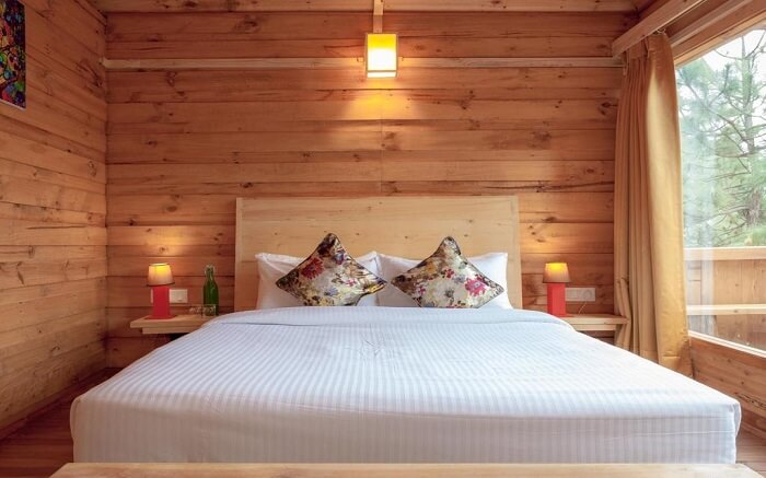 A beautiful wooden resort room with a white bed and glass window