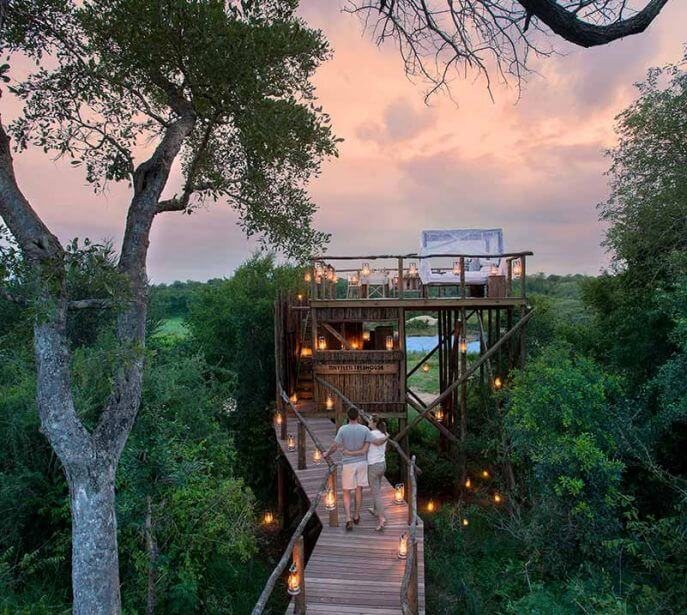 A couple walking the wooden bridge at Tinyeleti Treehouse in Lion Sands in Africa