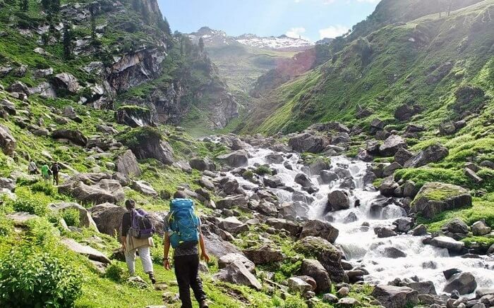 Travelers walking by the stream during Hampta Pass trek in Himachal