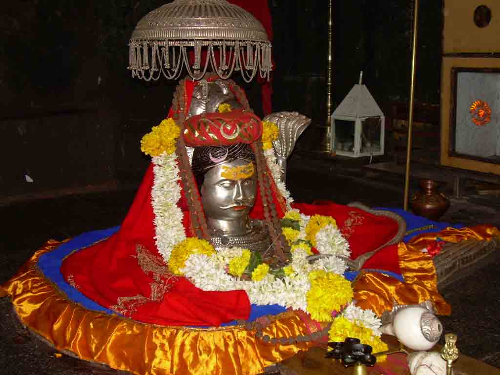 a metal god statue covered by flowers
