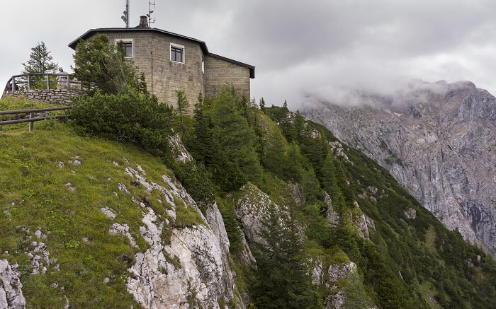a house at the end of a cliff overlooking mountains