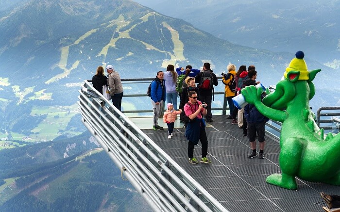 people standing on a platform overlooking mountains