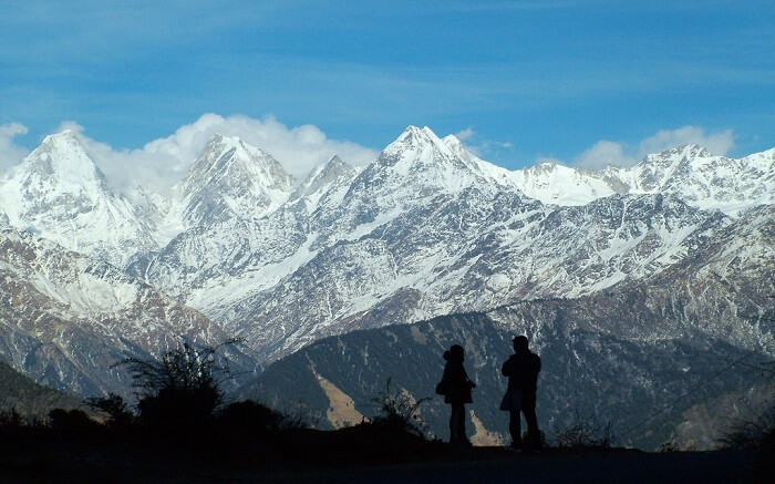 two travelers standing against the snowcovered mountains
