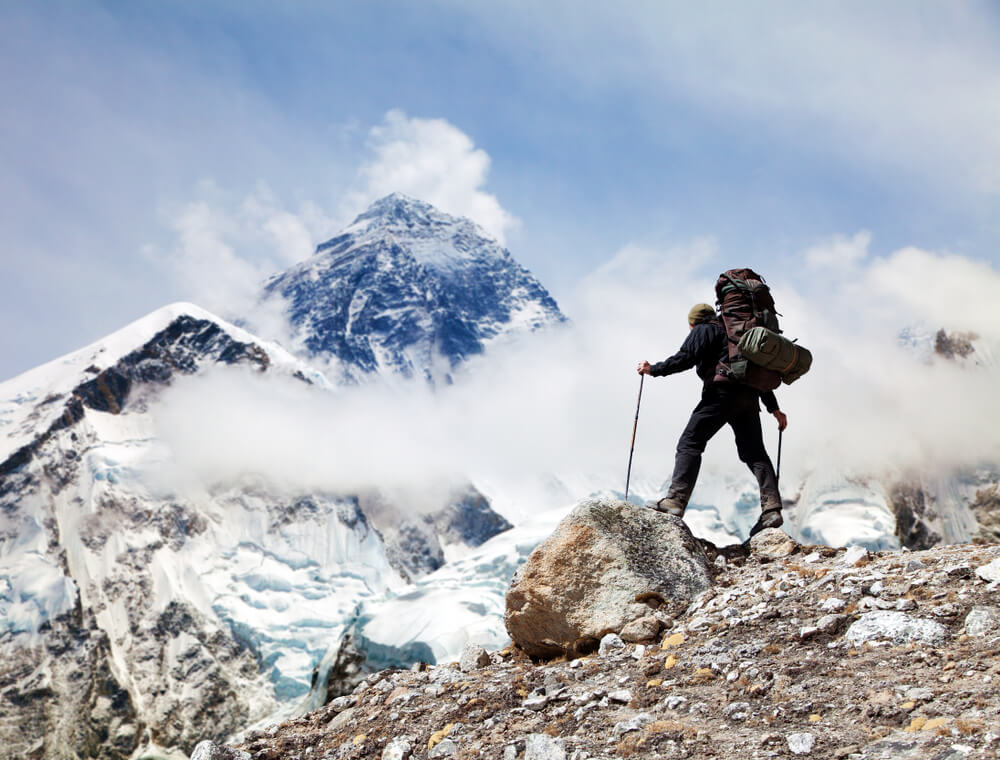 a man trekking in snow covered mountains